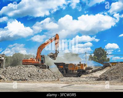 Cantiere edile con macchinari di demolizione che schiacciano attrezzature e cumuli di macerie durante la ristrutturazione Foto Stock