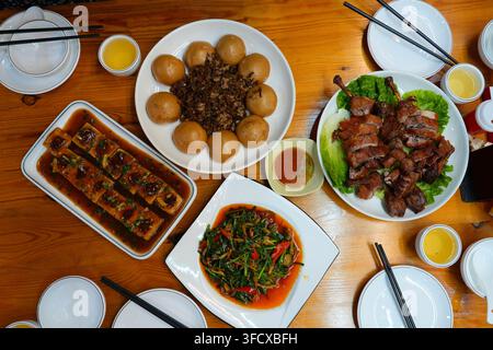 Tavolo da ristorante con molti piatti nella campagna di Guangdong, Cina. Cucina cantonese e cucina hunan. Tofu ripieno, waipo cai, cosce d’anatra e verdure saltate Foto Stock