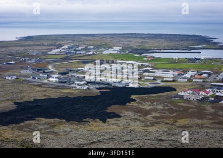 Vista aerea della città di Grindavik sulla penisola di Reykjanes, con case residenziali, il porto e un vasto campo di lava nera, Grindavi Foto Stock