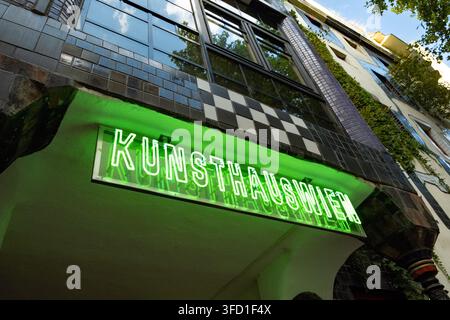 VIENA, AUSTRIA - 22 AGOSTO 2026: Insegna al neon illuminata di verde del museo Kunst Haus Wien sulla facciata a mosaico dell'edificio. Foto Stock