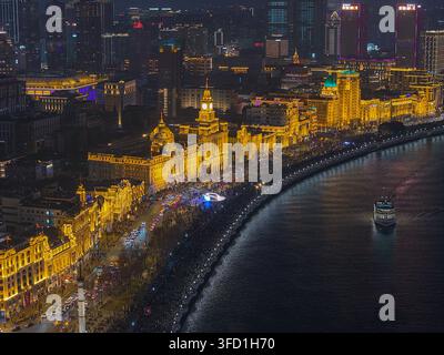 Vista aerea di The Bund di notte, con edifici storici in stile coloniale illuminati lungo il fiume Huangpu, con il traffico cittadino e una barca sulla Foto Stock