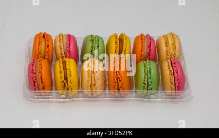 Dolci macarons tradizionali colorati in vassoio di plastica isolati su bianco Foto Stock
