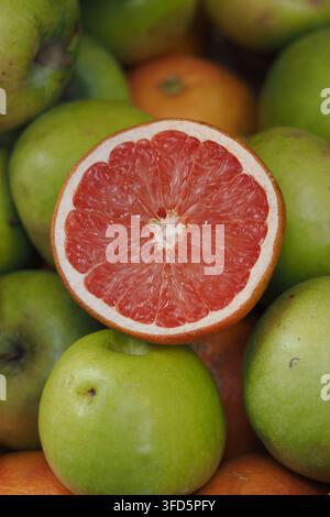Grapefruit tagliato a metà su un mucchio di mele verdi Foto Stock