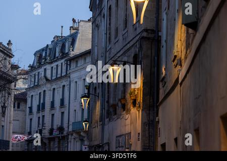 Avignone, Francia - 28 dicembre 2025: La notte cala su antiche strade di pietra, dove le lampade da parete gettano luce su architettura storica e tetti. Foto Stock