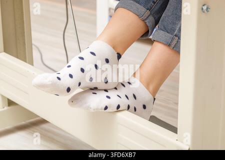 Piedi femmina sul pedale di una macchina da cucire, primo piano del motore Foto Stock