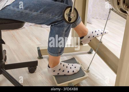 Piedi femmina sul pedale di una macchina da cucire, primo piano del motore Foto Stock