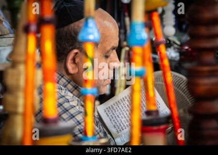 SHIRAZ, IRAN - 16 AGOSTO 2016: Uomo ebreo con kippa legge un libro di preghiere ebraico nel bazar di Shiraz, Iran, sulla comunità ebraica iraniana, fede, Foto Stock