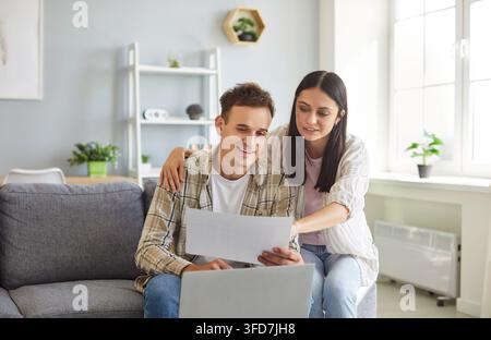 Coppia giovane che sbriga le pratiche, usa il laptop, gestisce le finanze, paga le tasse e le bollette dei servizi Foto Stock