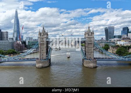 L'ammiraglia dei Sea Cadets, TS Royalist, naviga sotto il Tower Bridge sollevato sul Tamigi a Londra, Inghilterra, Regno Unito, il 28 giugno 2026. Foto Stock