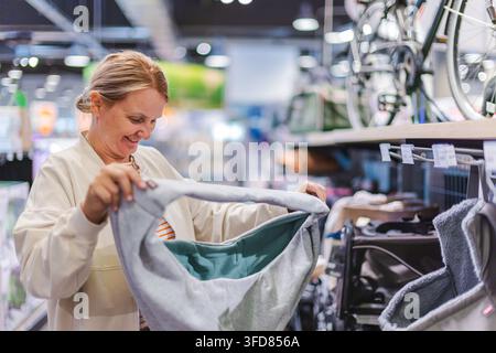Donna che ispeziona un lettino morbido grigio per animali nel negozio Foto Stock