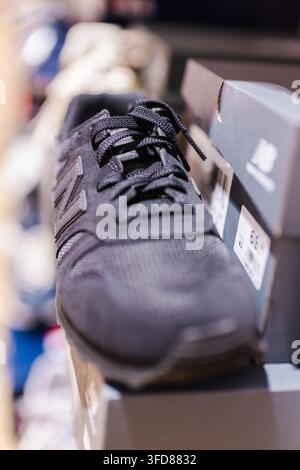 Prima piano di una scarpa sportiva nera accanto alla scatola di vendita al dettaglio Foto Stock