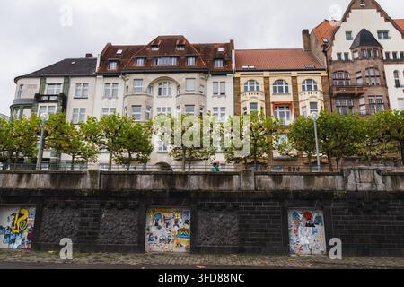 Facciate residenziali storiche sopra un muro coperto di graffiti a Düsseldorf Foto Stock