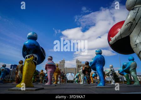 Un piano ad angolo ampio e basso mostra una serie di statue colorate di figure umane intitolate "Man of the World", ognuna delle quali tiene una sfera, che conducono verso un moderno Foto Stock
