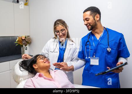 Squadra medica che consulta un paziente in clinica utilizzando un tablet digitale Foto Stock