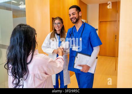 Medici che salutano un paziente con una stretta di mano nel corridoio dell'ospedale Foto Stock