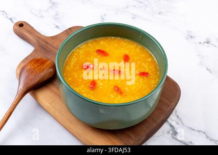 Porridge di miglio dorato e zucca guarnito con bacche di goji essiccate Foto Stock