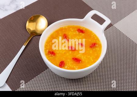 Porridge di miglio dorato e zucca guarnito con bacche di goji essiccate Foto Stock