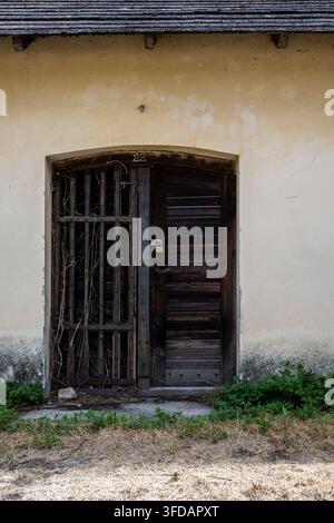 Una porta consumata, numerata 22, è chiusa con un pesante lucchetto per proteggere questa struttura invecchiata, mantenendo lo spazio interno conservato e inaccessibl Foto Stock