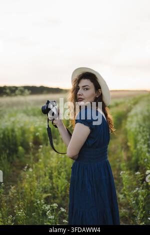 Fotografa sorridente che rivede le foto sulla fotocamera in un prato estivo Foto Stock