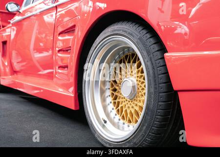 Londra, Regno Unito - 22 febbraio 2020: Primo piano di una ruota in lega a maglie dorate multipezzo montata su un’auto classica rossa modificata in mostra a un salone dell’auto a Londo Foto Stock