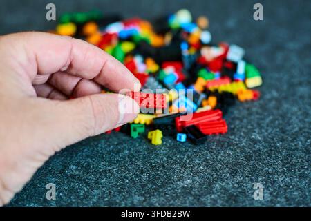 Un primo piano di una mano che tiene delicatamente mattoncini LEGO colorati. Rappresenta creatività, costruzione e sviluppo giocoso per varie applicazioni Foto Stock