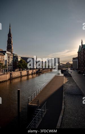 La chiesa di Santa Caterina si erge oltre il canale e l'architettura storica in mattoni vicino al quartiere di Speicherstadt di Amburgo. Foto Stock
