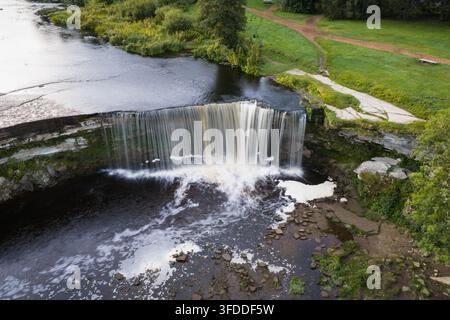 Vista aerea con drone della scenografica cascata di Jagala che scorre su una scogliera di calcare lungo il fiume Jagala in Estonia, che mostra la curva del fiume e l'acqua bianca Foto Stock