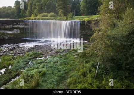 Vista panoramica del paesaggio della cascata di Jagala che scorre su una scogliera di calcare, incorniciata da erba verde rigogliosa e alberi sulla riva del fiume in Estonia. Foto Stock
