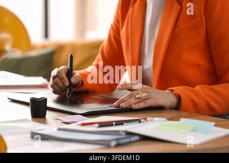 Design creativo e flusso di lavoro digitale, grafico professionista che utilizza un tablet per illustrazione e ritocco in un ambiente di ufficio moderno Foto Stock