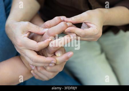 Anziana donna coreana che massaggia le articolazioni dolorose delle dita in un primo piano Foto Stock