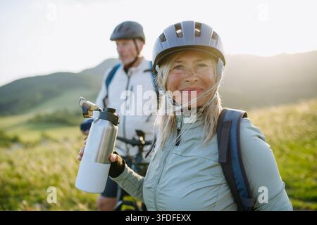 Coppia matura che si riposa e beve acqua durante un'escursione in bicicletta. Foto Stock