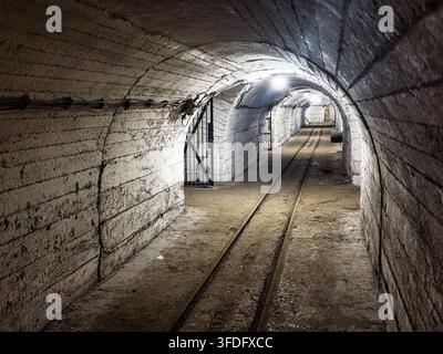All'interno di un famoso vecchio tunnel con parete bianca, miniera sotterranea. Le pareti di pietra ruvida contribuiscono all'atmosfera oscura e misteriosa di questo passaggio abbandonato Foto Stock