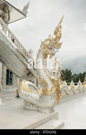 Chachoengsao, Thailandia - 29 agosto 2026: Una scultura ornata di Naga si erge accanto a un edificio di un tempio thailandese a Chachoengsao. Foto Stock