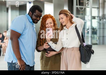 Diversi amici di lavoro che ridono insieme davanti a uno smartphone Foto Stock