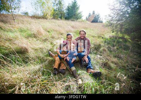 Famiglia felice di cinque persone che si rilassa in un campo soleggiato Foto Stock