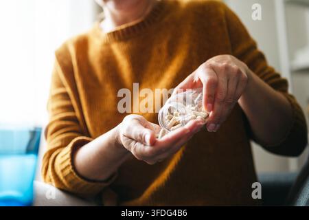 Donna che versa capsule di integratore nella propria mano Foto Stock