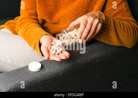 Donna che versa capsule di medicinali da una bottiglia nella mano Foto Stock