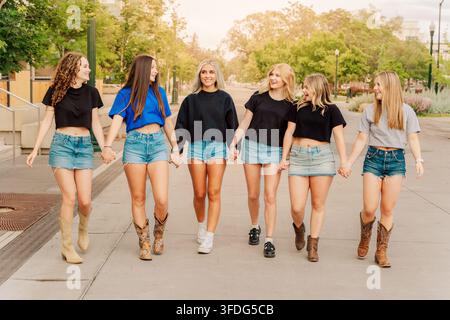 Gruppo di giovani donne felici che camminano tenendosi per mano Foto Stock