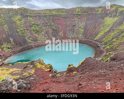 Vista aerea del cratere Kerid con il suo lago turchese circondato da pendici rocciose vulcaniche rosse a Grimsnes, Islanda. Foto Stock