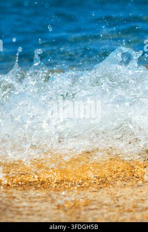 Vista ravvicinata di un'onda del mare che rotola dolcemente su una spiaggia di sabbia, con l'acqua schiumosa dell'oceano che si sparge lungo la linea costiera. Scena costiera naturale con Foto Stock