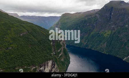 Prospettiva a droni di un fiordo norvegese circondato da scogliere rocciose verticali e da una fitta foresta di conifere. Foto Stock