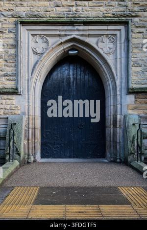 Pesanti porte doppie in legno scuro con cerniere di ferro ornate sotto un arco di pietra alla Chiesa di San Tommaso e San Giovanni, Radcliffe, Lancs, Regno Unito. Foto Stock