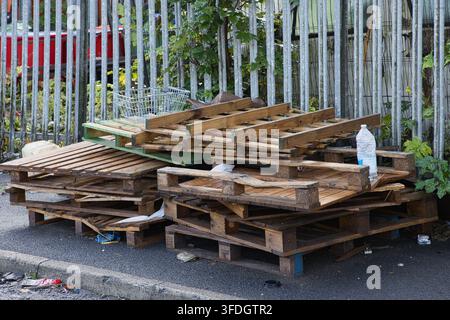 Pallets di legno abbandonati e un cestino della spesa scaricati illegalmente sul marciapiede accanto alle ringhiere metalliche di Milltown Street a Radcliffe, Lancs, Regno Unito. Foto Stock