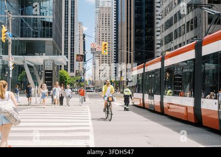 Toronto, Canada - 20 giugno 2026: Scenario di strada del centro con ciclista, pedoni e tram Foto Stock