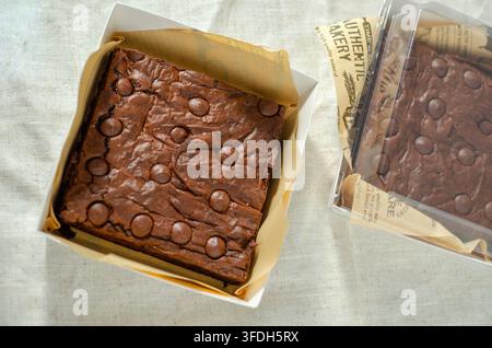 Vista dall'alto di pezzi di brownie al cioccolato fondenti disposti su una superficie leggera e ruvida. Foto Stock
