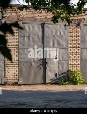 Porta del garage in metallo grigio chiusa su muro di mattoni bianchi Foto Stock