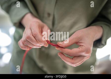 Donna piega un cavo USB sfilacciato con entrambe le mani, cercando una posizione affidabile per caricare il telefono. Foto Stock