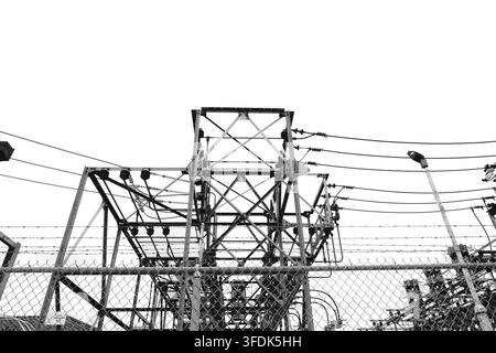 Strutture di trasmissione elettrica dense, linee elettriche e apparecchiature di servizio fotografate in bianco e nero ad alto contrasto. Foto Stock