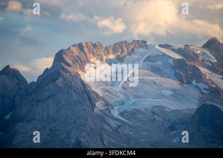 Vista del ghiacciaio della Marmolada e delle vette rocciose delle Dolomiti sotto un cielo soffice al tramonto nel Veneto, Italia. Foto Stock