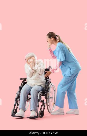 Abuso agli anziani e stress degli assistenti, infermiera che urla a una donna anziana in sedia a rotelle con problemi di salute mentale e traumi emotivi su sfondo rosa Foto Stock